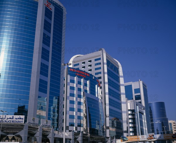 UAE, Dubai, Dubai Concorde Hotel and Residence on Al Maktoum Road.  Modern glass fronted exterior of hotel beside offices or apartments to let and advertising hoarding.