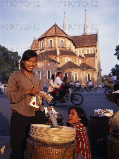 VIETNAM, South, Ho Chi Minh City, Female street hawkers selling snacks in front of Notre Dame Cathedral.