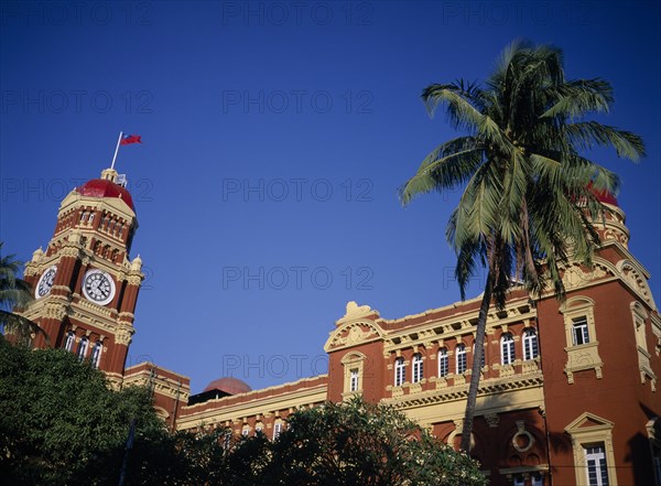 MYANMAR, Yangon, Part view of exterior of historic post office building and clock tower with palm tree in foreground.