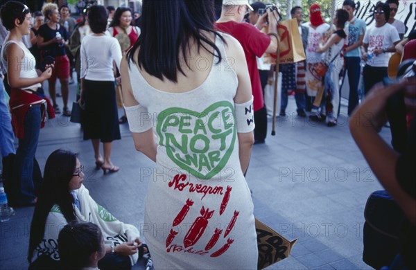 THAILAND, Bangkok, Anti-war rally outside MBK shopping mall protesting against Bush and Blair.  Woman wearing dress with Peace Not War slogan printed on back.