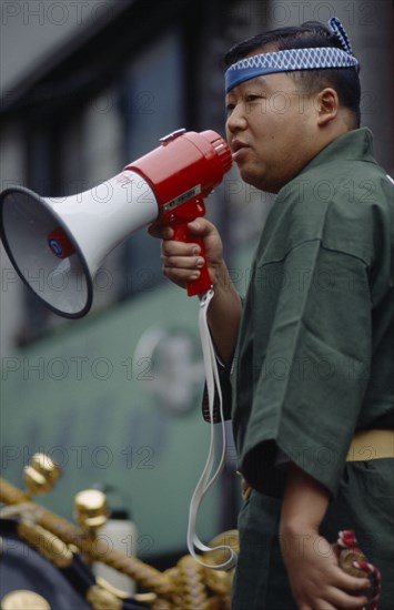 JAPAN, Honshu, Tokyo, Man with megaphone directing participants in Sanja Matsuri Festival.