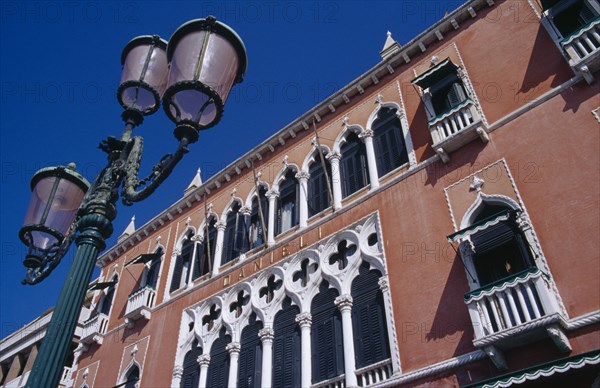 ITALY, Veneto, Venice, Terracotta and white painted facade of the Danieli Hotel with street lamp in foreground.