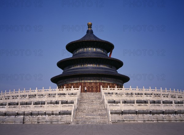 CHINA, Beijing, Temple of Heaven.  Hall of Prayer for Good Harvests with western tourist standing at top of steps to entrance.