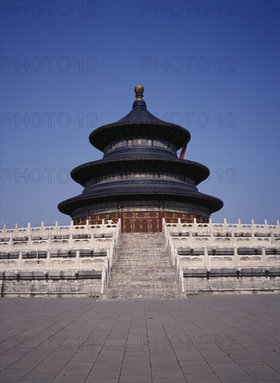 CHINA, Beijing, Temple of Heaven.  Hall of Prayer for Good Harvests with western tourist standing at top of steps to entrance.