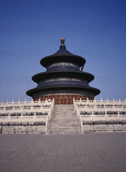 CHINA, Beijing, Temple of Heaven. Hall of Prayer for Good Harvests with western tourist standing at top of steps to entrance.