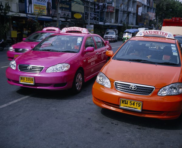 THAILAND, Bangkok, Pink and orange taxi cabs on busy road.