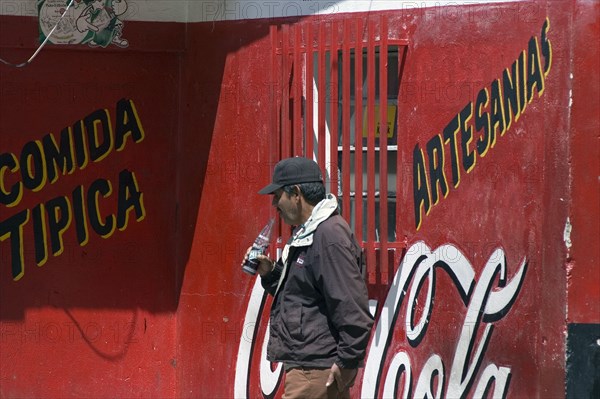 VENEZUELA, Merida state, Apartaderos, "Man drinking a soft drink next to a Coca Cola advert, Apartaderos village, Venezuelan Andes (Close to Merida), "