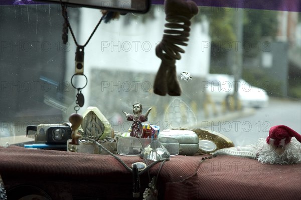 VENEZUELA, Caracas , "Dashboard of Caracas taxi including religious artefacts, a comb and reading glasses."