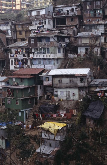 INDIA, West Bengal, Darjeeling, Poor quality housing on steep hillside strewn with litter.