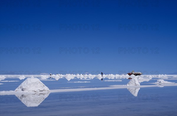 BOLIVIA, Potosi, Salar de Uyuni, Salt flats with salt piled up ready to be collected by truck.