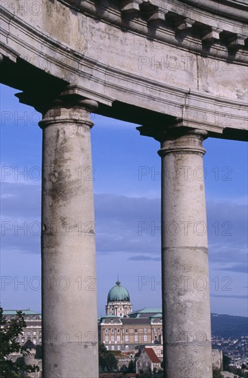HUNGARY, Budapest, Copper dome of the Royal Palace rooftop and cityscape seen between stone pillars of St Gellert memorial. Eastern Europe