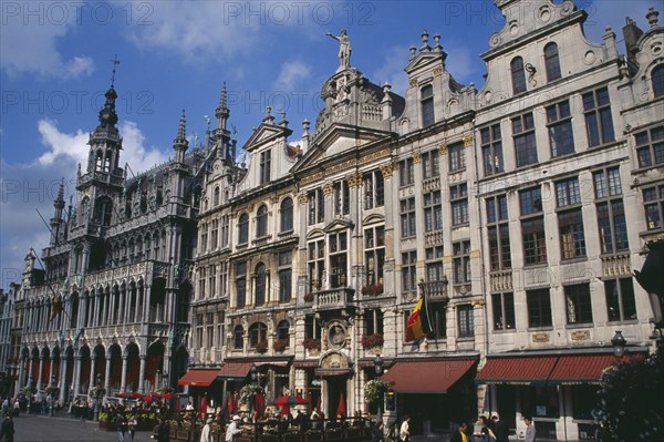 BELGIUM, Brabant, Brussels, Grand Place.  Maison du Roi on left beside decorative facades of old town buildings  busy outside tables of cafe and people crossing square. UNESCO World Heritage Site