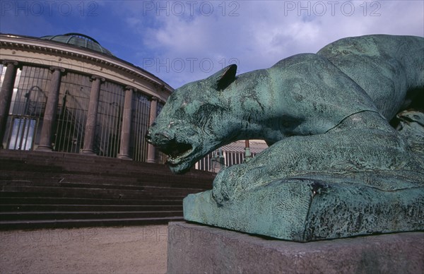 BELGIUM, Brabant, Brussels, Botanical gardens.  Circular glass house with bronze statue of crouching lion or panther in foreground. greenhouse