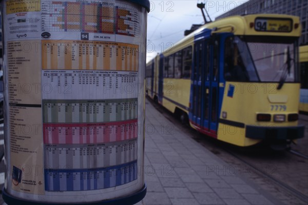 BELGIUM, Brabant, Brussels, Sign detailing tram times with passing tram beyond.