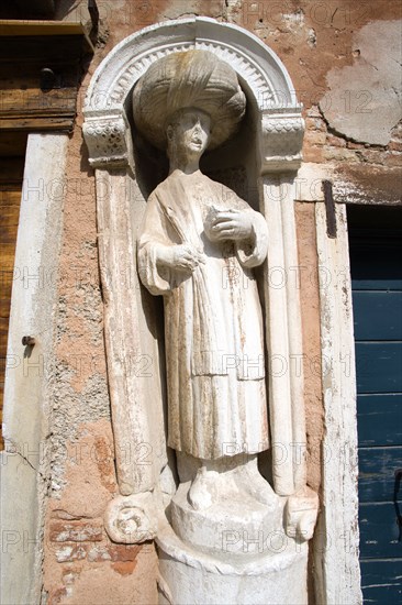 ITALY, Veneto, Venice, One of the three stone statues of Moors which gave the name to Campo dei Mori. This turbanned one is beside the front door of Tintoretto's house at 3399 Fondamente dei Mori in the Cannaregio district