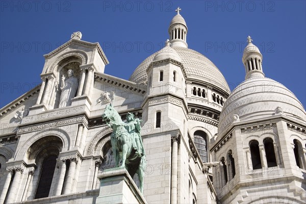 FRANCE, Ile de France, Paris, Montmartre The Church of Sacre Coeur or Sacred Heart with the bronze equestrian statue of Joan of Arc in the foreground