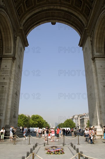 FRANCE, Ile de France, Paris, Tourists beside the Tomb of The Unknown Soldier under the main arch of the Arc de Triomphe in Place Charles de Gaulle with La Defence on the horizon