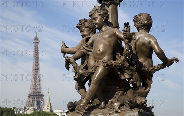 FRANCE, Ile de France, Paris, "Art Nouveau cherubs on a lamp-post on Ponte Alexandre III bridge across the River Seine named after Tsar Alexander III of Russia, with the Eiffel Tower in the distance"