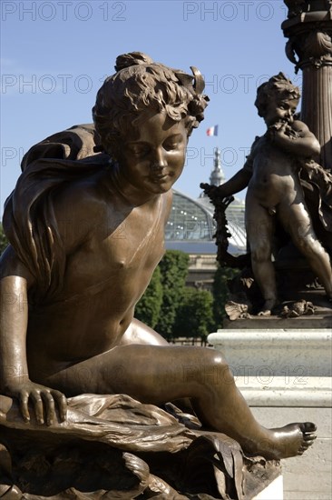 FRANCE, Ile de France, Paris, Art Nouveau cherubs on a lamp-post on Ponte Alexandre III bridge across the River Seine named after Tsar Alexander III of Russia with the Grand Palais beyond