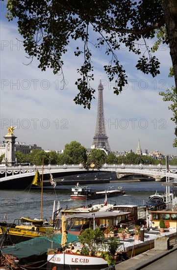 FRANCE, Ile de France, Paris, Houseboat barges moored alongside Port des Champs Elysees on the River Seine by the Ponte Alexandre III with the Eiffel Tower in the distance