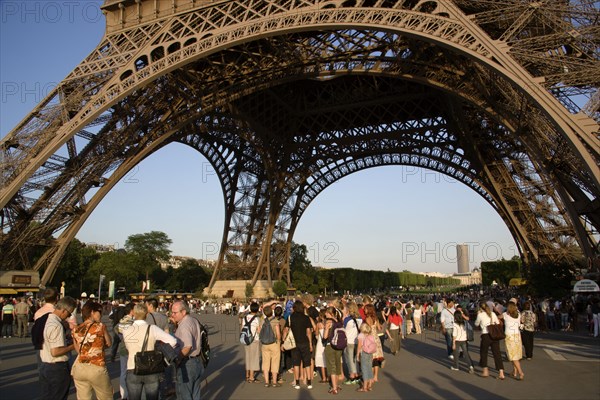 FRANCE, Ile de France, Paris, Tourists at the base of the Eiffel Tower near sunset