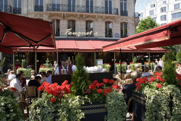 FRANCE, Ile de France, Paris, Fouquet's brasserie on the Champs Elysees with waiter and customers at pavement tables under sun shade umbrellas