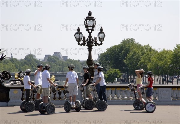 FRANCE, Ile de France, Paris, "Children on the Pont Alexandre III across the River Seine. Touring on electric self balancing scooters, or two wheeled gyroscopic platform"