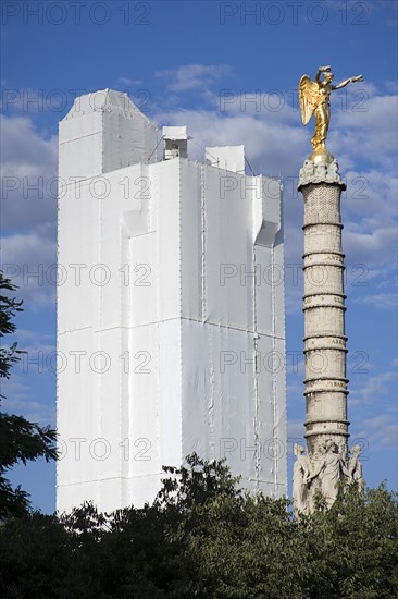 FRANCE, Ile de France, Paris, Les Halles. A gilded statue on top of a column in Place du Chatelet with the Tour St Jacques under scaffolding and fabric beyond whilst undergoing restoration