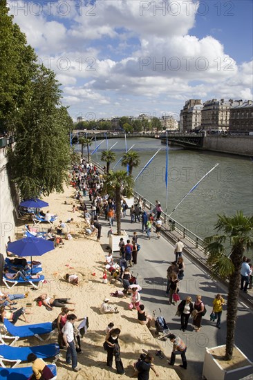 FRANCE, Ile de France, Paris, The Paris Plage city beach on the right bank of the River Seine where the road is closed and people lie in the sand and walk along the river bank