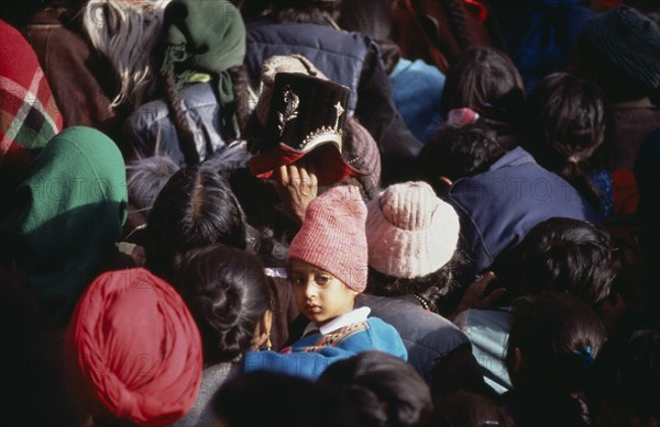 INDIA, Ladakh, Hemis Gompa, "Child in crowd of pilgrims reaching for Holy Thangka of Padmasambhava during Hemis Festival to celebrate the birth of Guru Padmasambhava, founder of Tibetan Buddhism."