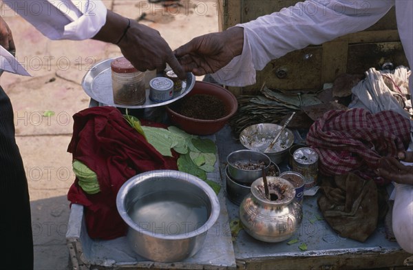 INDIA, North, Markets, Cropped shot of paan seller making transaction with customer across stall with paan leaves and other ingredients.