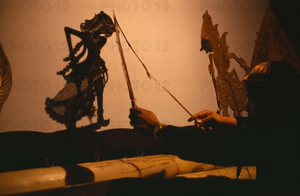 INDONESIA, Java, Shadow Puppets, "Wayang Kulit shadow puppet performance.  Puppet master or Dalang at work, he tells the story, speaks all the voices and conducts the gamelan music."