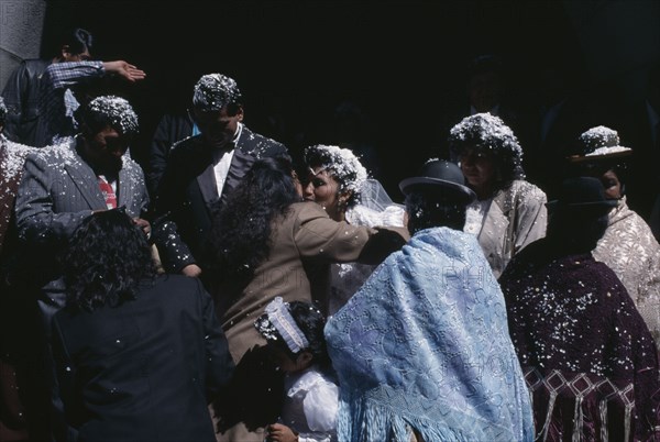 BOLIVIA, La Paz, Friends and family congratulate wedding bride and groom covered with white confetti on the steps of the Basilica de San Francisco.