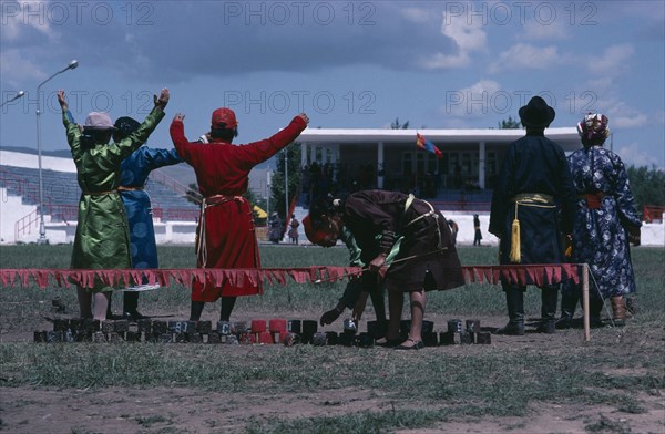 MONGOLIA, Sport, National Day archery contest.  Target line with red marking the bullseye and scorers signalling to competitors.