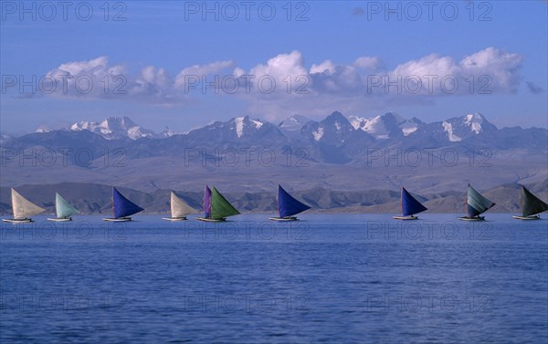 BOLIVIA, La Paz, Lake Titicaca, Isla Suriqui.  Boats with coloured sails taking part in sailing regatta with mountain backdrop.