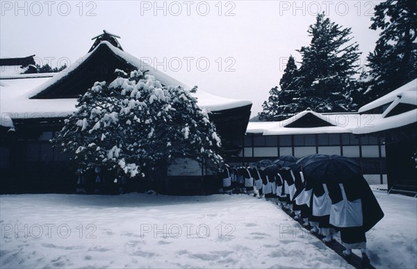 JAPAN, Honshu, Kii Peninsula, Mount Koya-san.  Venerated Shingon-Buddhist site.  Line of monks wearing black and white robes returning to monastery in thick snow.