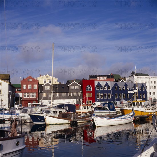 DENMARK, Faroe Islands, Torshavn, Boats moored in harbour with colourful waterfront buildings behind.