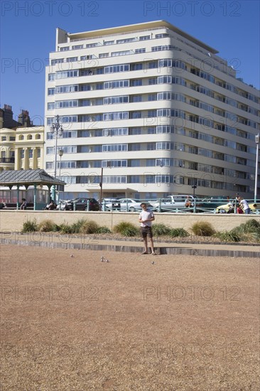 ENGLAND, East Sussex, Brighton, "Embassy Court restored Art Deco apartment block on the sea front, with petanque pitch in the foreground."