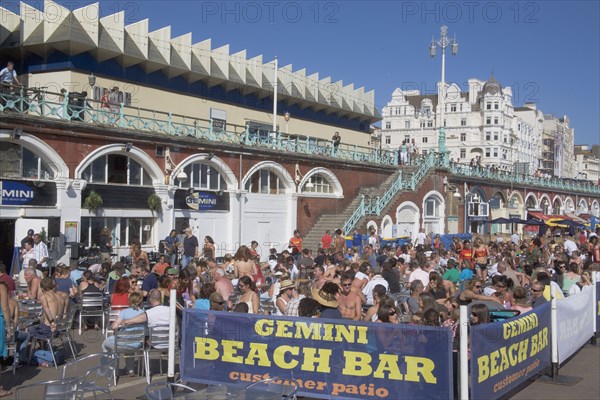 ENGLAND, East Sussex, Brighton, People sat outside the Beach Bar on the seafront.
