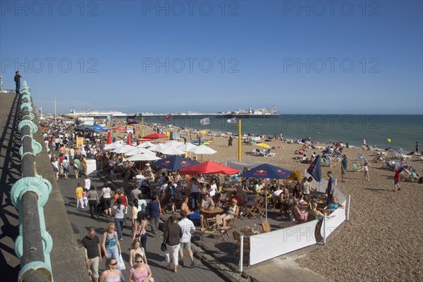 ENGLAND, East Sussex, Brighton, People sat at tables outside seafront bars and cafes.