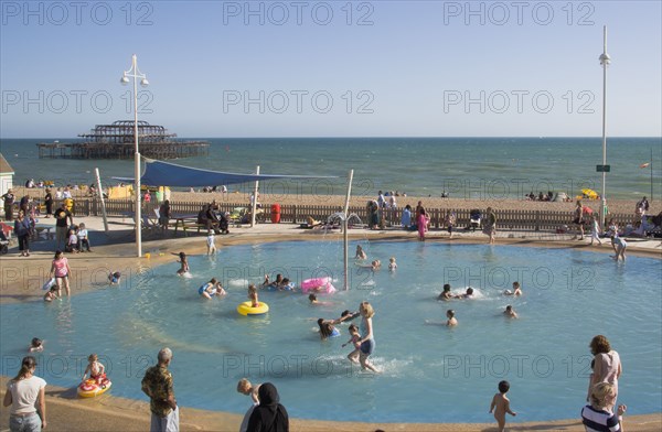 ENGLAND, East Sussex, Brighton, Childrens paddling pool with the ruins of the West Pier behind.