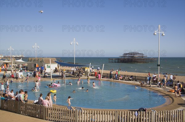 ENGLAND, East Sussex, Brighton, Childrens paddling pool with the ruins of the West Pier behind.