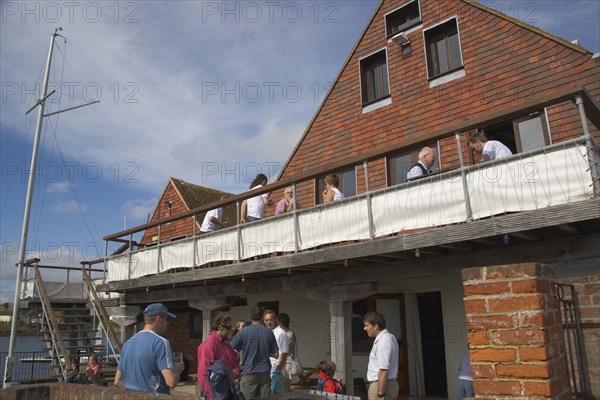 ENGLAND, Hampshire, Emsworth, People sat outside the yacht club.