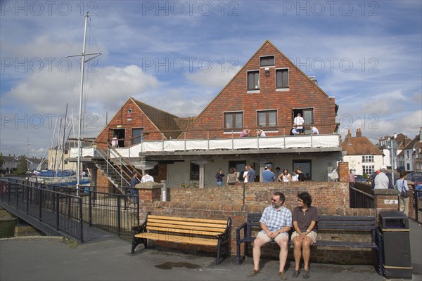 ENGLAND, Hampshire, Emsworth, People sat outside the yacht club.