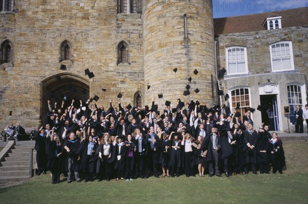 EDUCATION, University, Graduation, "Graduate wearing their mortar boards and gowns, posing for a group photo. Some motar board having been thrown in the air."