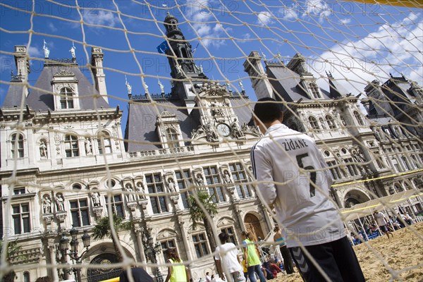 FRANCE, Ile de France, Paris, The Paris Plage urban beach. Boy wearing a Zidane football shirt playing in goal during a beach soccer childrens match in front of the Hotel de Ville Town Hall