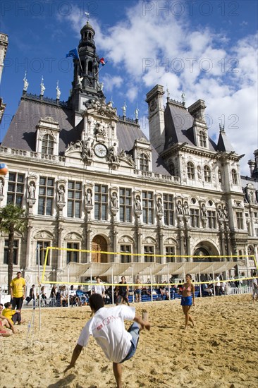 FRANCE, Ile de France, Paris, The Paris Plage urban beach. Young people playing beach volleyball in front of the Hotel de Ville Town Hall