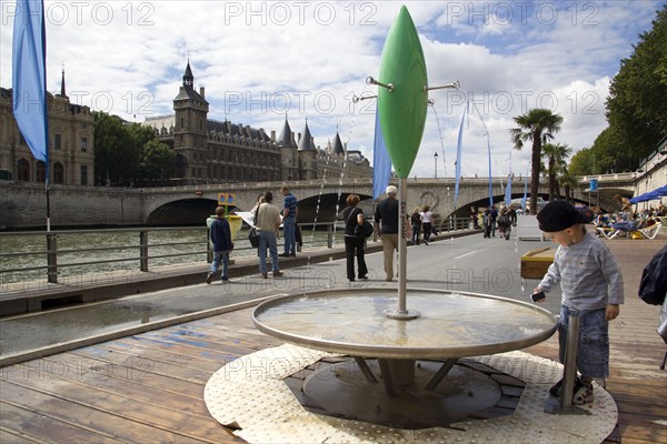 FRANCE, Ile de France, Paris, "The Paris Plage urban beach. A small boy at one of the many free drinking water fountains on the Voie Georges Pompidou, a usually busy road closed to traffic, opposite the Ile de la Cite "