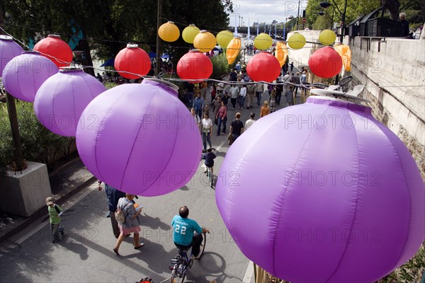 FRANCE, Ile de France, Paris, The Paris Plage urban beach. Colourful lanterns hanging above pedestrians strolling along the Voie Georges Pompidou a usually busy road closed to traffic opposite the Ile de la Cite