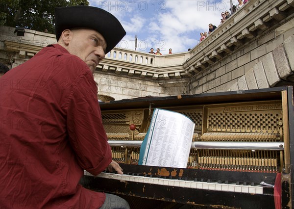 FRANCE, Ile de France, Paris, The Paris Plage urban beach. A singer playing a piano to an audience under the Pont Notre Dame on the Voie Georges Pompidou a usually busy road closed to traffic